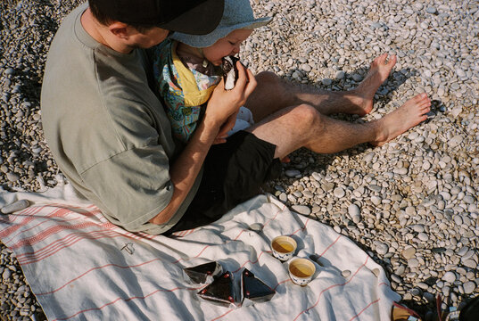 Young father feeding baby on the beach
