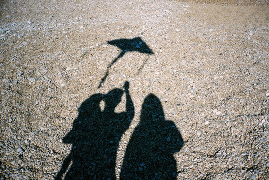 Silhouettes of a couple with baby flying a kite 