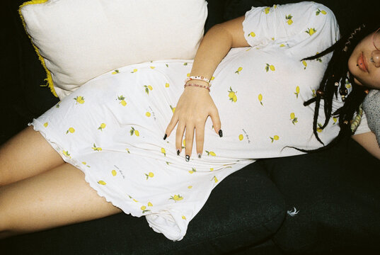 Young Woman Relaxing on Couch in Patterned Dress with Direct Flash