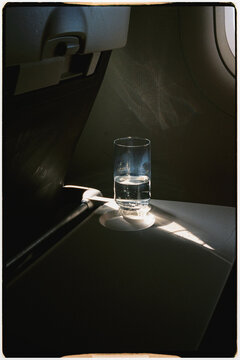 Close-up of glass of water lit by sunlight on the table of an airplane