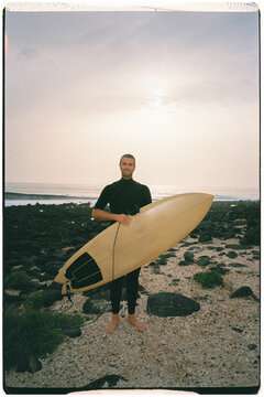 Analog portrait of a surfer posing cheerfully with his surfboard