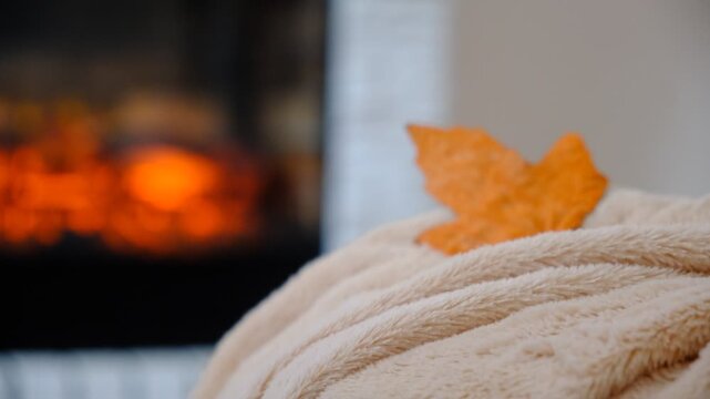 Fireplace and fluffy warm beige blanket. Autumn whispers through the window, while inside, warmth and comfort reign supreme. Snuggled under a soft, warm blanket by the crackling fireplace