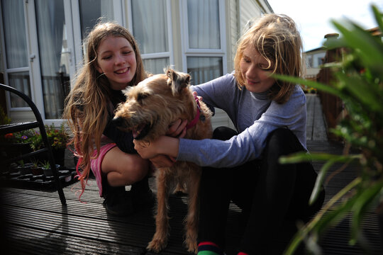 2 girls hug and play with their dog