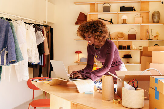 Businesswoman using laptop in clothing store workspace