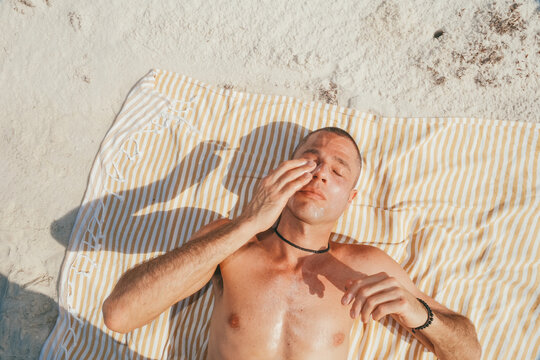 Man lying on beach wearing sunscreen