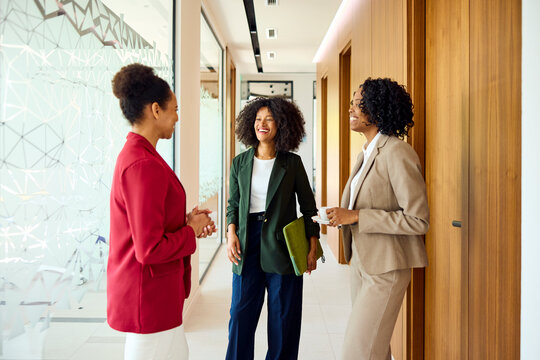 Women converse in a company's hallway.