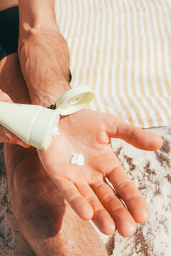 Man dispensing sunscreen into hand at beach