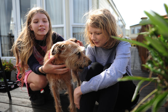 2 girls hug and play with their dog