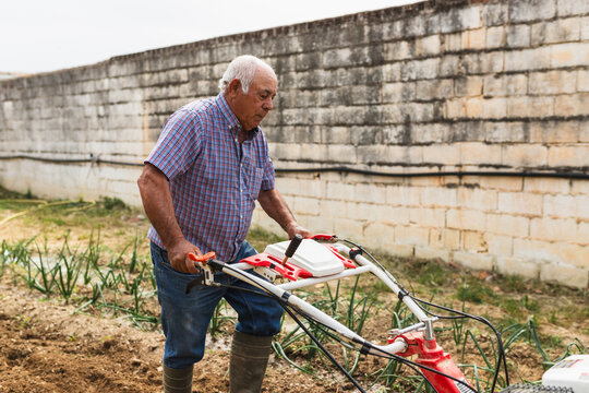 Senior Male Operating Motorized Cultivator in Rural Plot