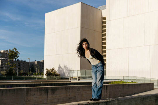 Woman posing on urban concrete barrier 