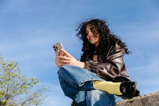 Young woman smiling using smartphone outdoors
