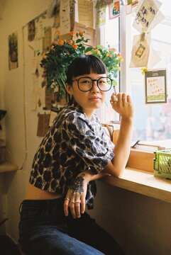 Young Woman Smoking by Window in Warm Natural Light