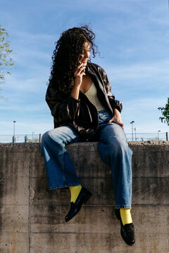 Woman sitting on wall talking cell phone