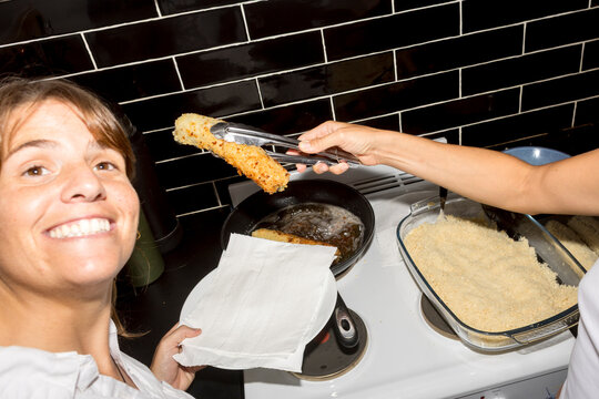 UGC Woman lifting fried sushi roll from pan with direct flash