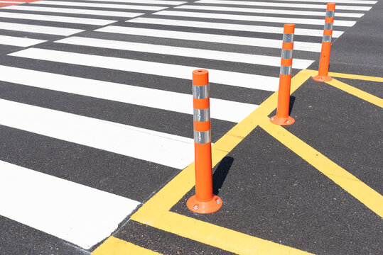 Orange traffic cone beside zebra crossing with yellow lines