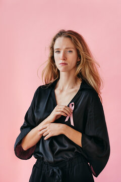 Captivating Woman Embraces Awareness With a Pink Ribbon Backdrop