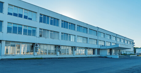 Long low industrial office building with air conditioning units and paved forecourt at sunrise © ossyffer