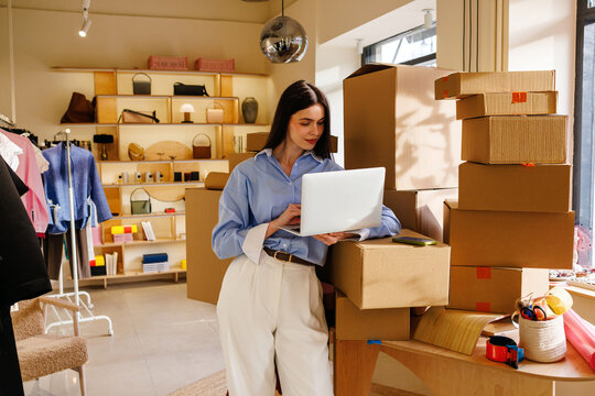 Woman using laptop for ecommerce in small business boutique workspace