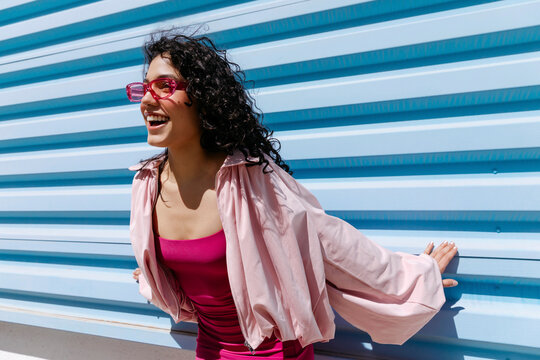 Woman wearing pink sunglasses laughing 