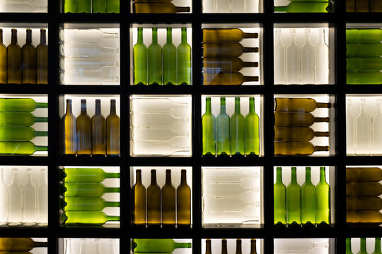 Backlit wall of wine bottles in geometric grid