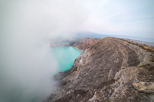 Volcanic crater lake emerging through clouds in Ijen Indonesia