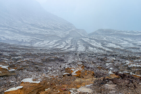 Foggy volcanic crater landscape with eroded terrain in Ijen Indonesia