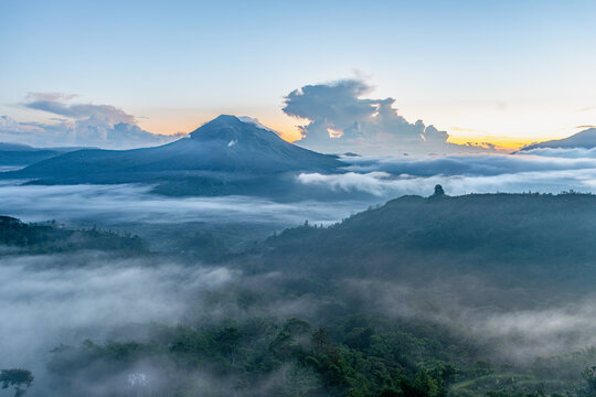 Bali volcano at sunrise with misty jungle and clouds