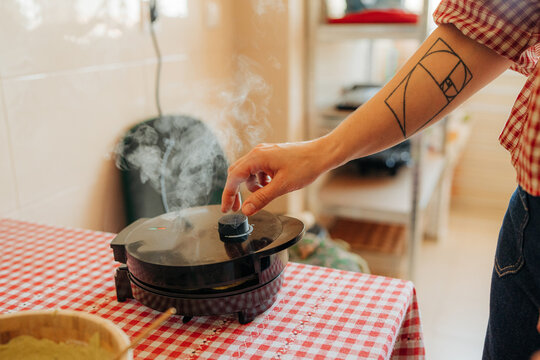 Hand opening waffle maker with steam in kitchen
