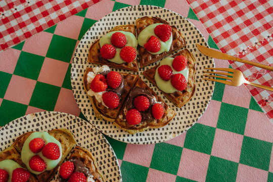 Close up of waffles with raspberries and cream topping