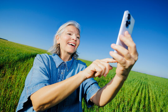 Happy smiling woman interacting with smartphone under blue sky