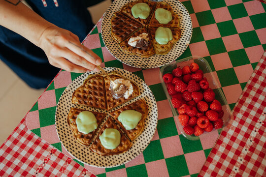 Homemade waffles with cream and raspberries on checkered table