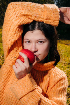 Model Holds Red Apple While Looking at camera