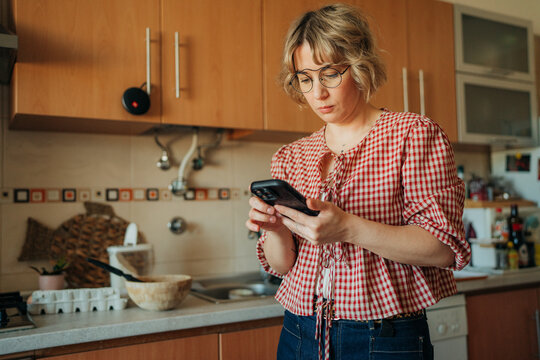 Woman ordering groceries online while cooking in kitchen