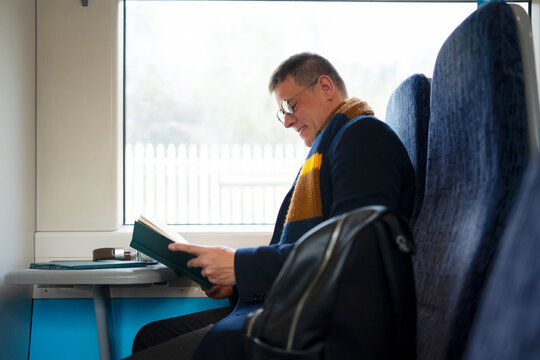 Man reading book during train commute