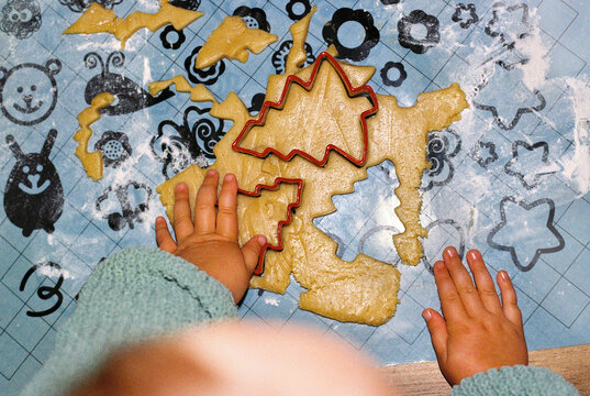 Anonymous girl's hands cutting out gingerbread cookies.