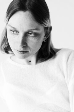 Woman Wears White Sweater and Poses for a Close-Up in Simple Setting