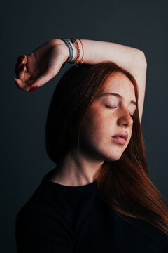 Teenage girl with red hair posing in moody studio light