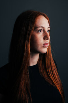 Thoughtful teenage girl portrait in moody studio light