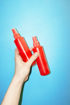 Hand holding bright red spray bottles with hard direct flashlight