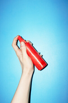 Hand holding bright red spray bottles with hard direct flashlight