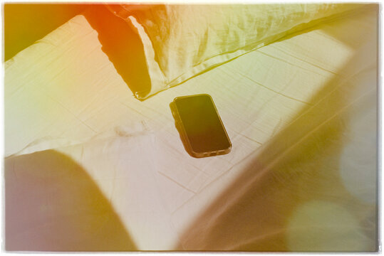 Smartphone Resting on Bed in Warm Morning Light