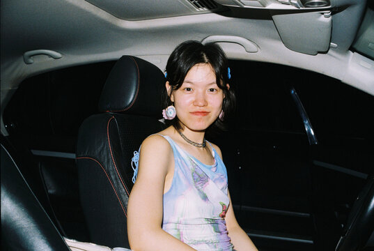 Night Drive &mdash; Young Woman Smiling in Driver&rsquo;s Seat Under Flash