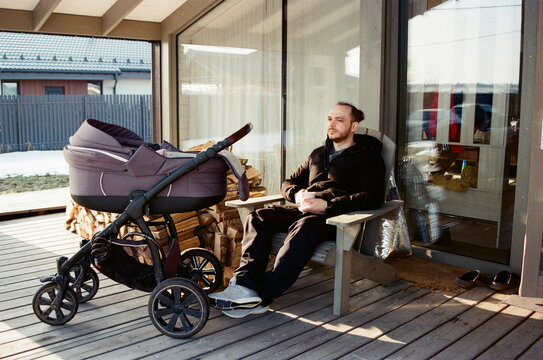 Man sitting on porch next to baby stroller