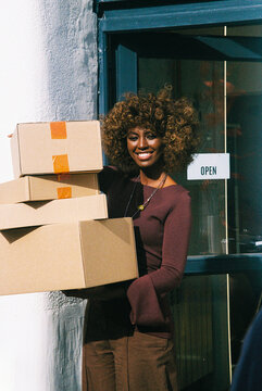 Woman carrying boxes outside shop film photo