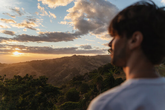 Person observing sunset landscape over mountain valley