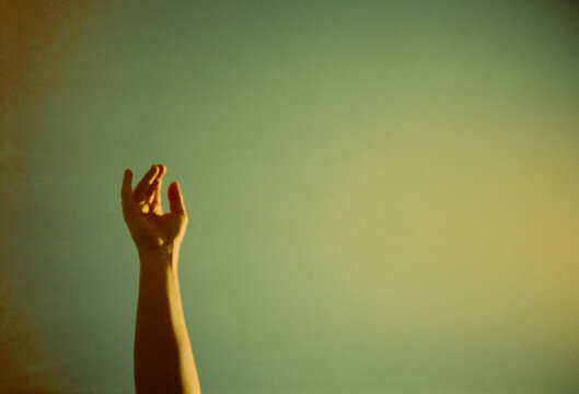 Reaching Hand Against a Bright Background in Warm Colors