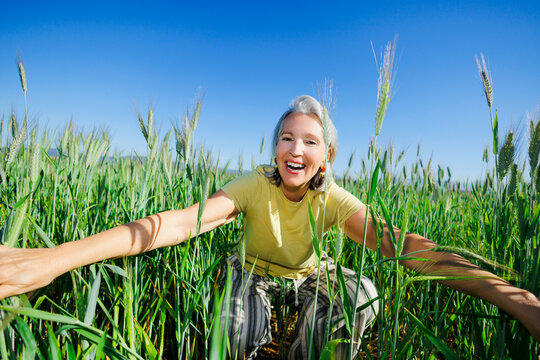 Happy woman enjoying nature in green field under blue sky
