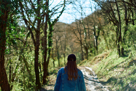 Woman walking through the forest under the shadows of the trees