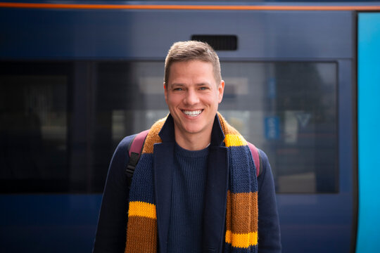 Young traveler smiling beside train at station