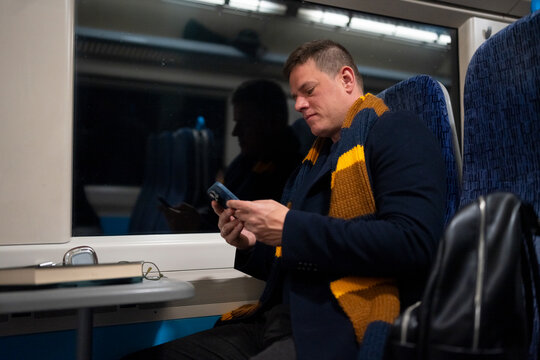 Commuter using smartphone inside train at night